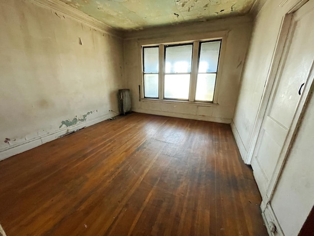 unfurnished room featuring ornamental molding, radiator, and dark wood-type flooring