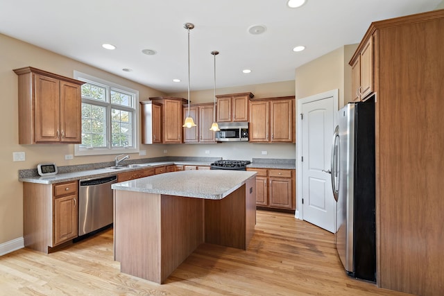 kitchen featuring a kitchen island, stainless steel appliances, decorative light fixtures, and light hardwood / wood-style floors