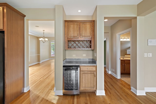 kitchen featuring a chandelier, light hardwood / wood-style floors, black fridge, and beverage cooler