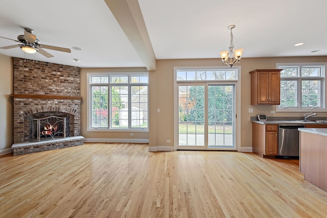 interior space with ceiling fan with notable chandelier, light wood-type flooring, sink, and a brick fireplace