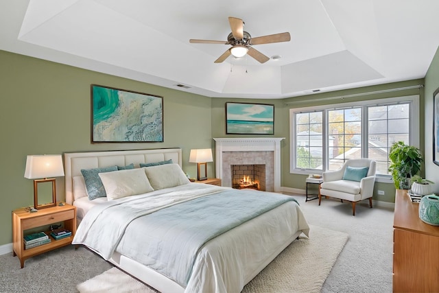 bedroom featuring a raised ceiling, ceiling fan, and light colored carpet