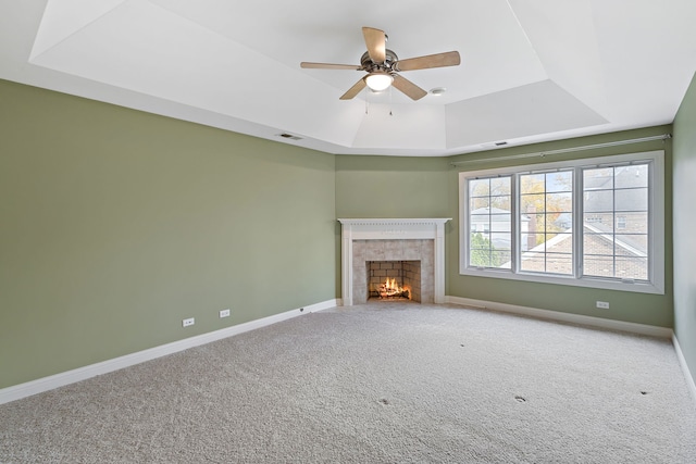 unfurnished living room featuring a tile fireplace, carpet, and a raised ceiling