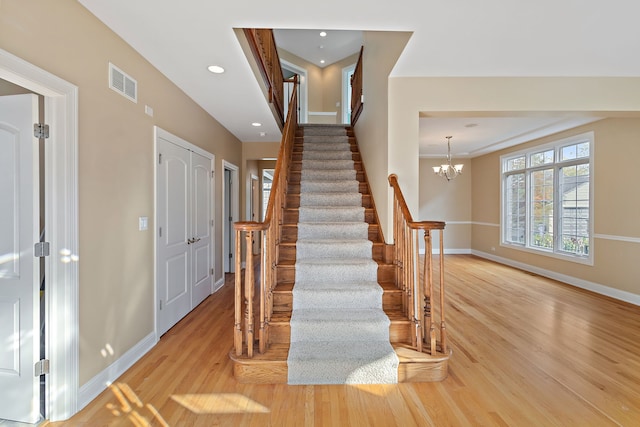 stairs with hardwood / wood-style floors and a notable chandelier