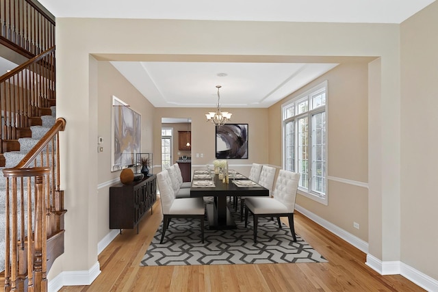 dining room with a wealth of natural light, an inviting chandelier, and light wood-type flooring