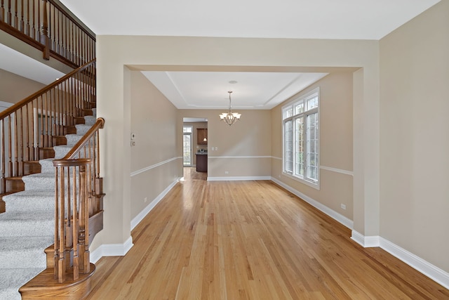 interior space featuring a notable chandelier, light hardwood / wood-style floors, and a tray ceiling