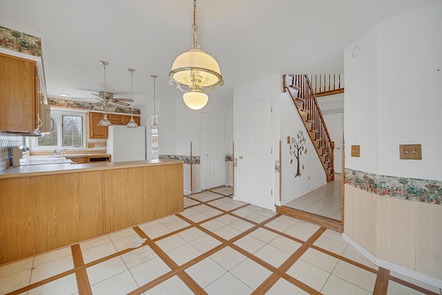 kitchen featuring ceiling fan, hanging light fixtures, white refrigerator, kitchen peninsula, and light tile patterned floors