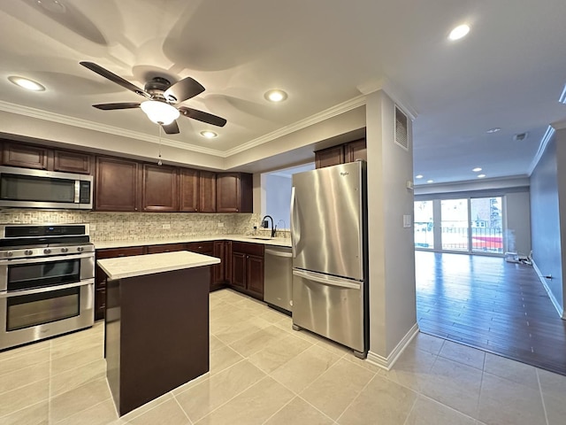 kitchen with decorative backsplash, ornamental molding, stainless steel appliances, sink, and a center island