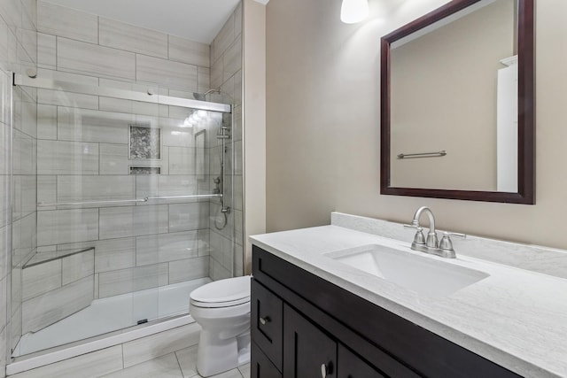 bathroom with tile patterned floors, vanity, toilet, and a shower with door