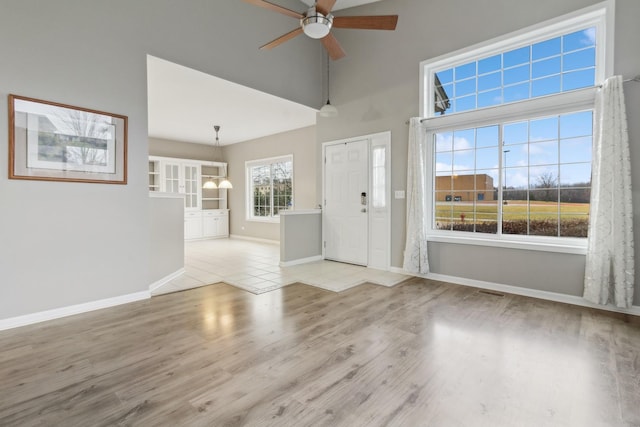 foyer entrance with ceiling fan, light hardwood / wood-style floors, and a high ceiling