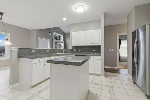 kitchen featuring white cabinets, stainless steel fridge, decorative light fixtures, and a kitchen island