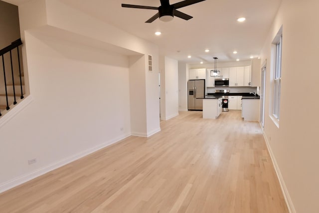 unfurnished living room featuring ceiling fan and light wood-type flooring