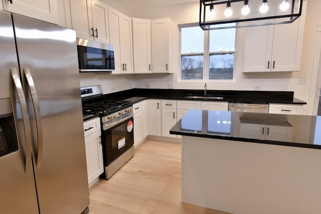 kitchen with white cabinetry, hanging light fixtures, and appliances with stainless steel finishes