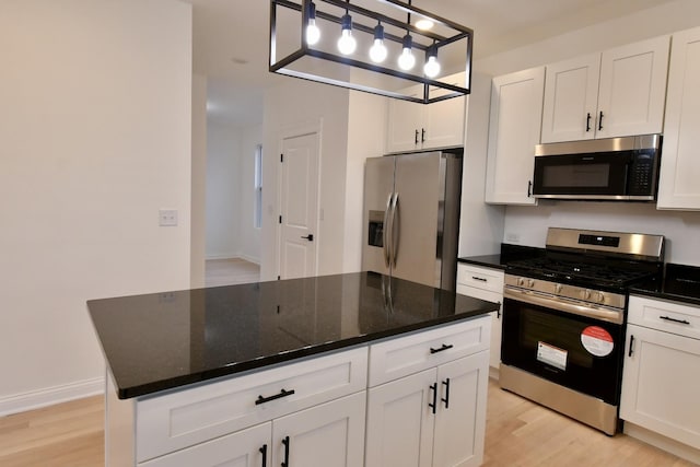 kitchen with white cabinets, appliances with stainless steel finishes, light hardwood / wood-style flooring, and pendant lighting