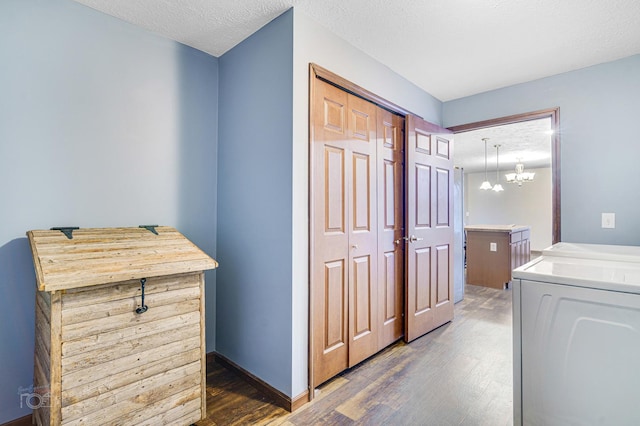 clothes washing area with a textured ceiling, washer and clothes dryer, dark hardwood / wood-style floors, and a notable chandelier