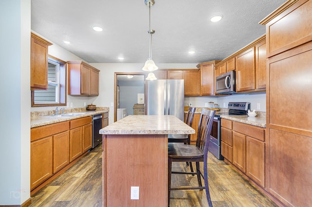 kitchen featuring appliances with stainless steel finishes, dark hardwood / wood-style flooring, washer and dryer, a center island, and hanging light fixtures