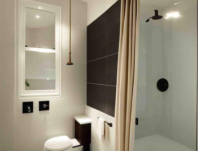 bathroom featuring tiled shower, toilet, and tile walls