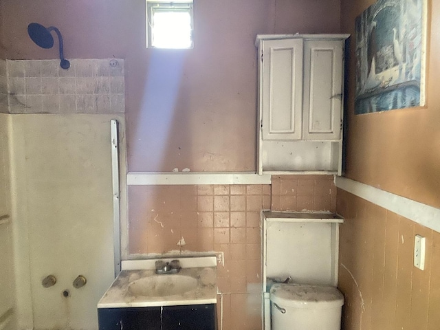 bathroom featuring tile walls and toilet