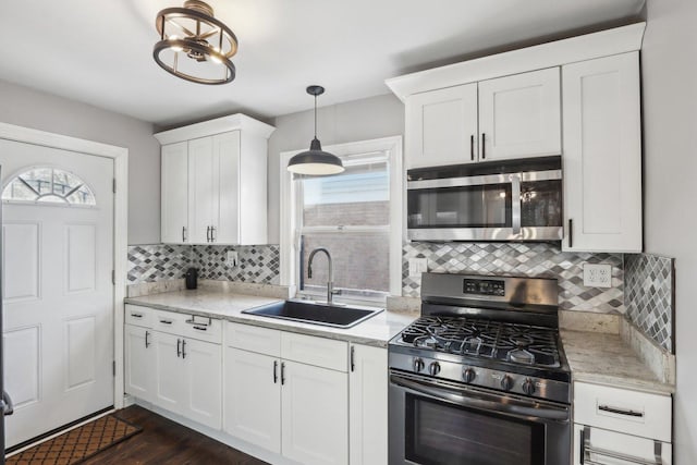 kitchen featuring decorative backsplash, stainless steel appliances, sink, pendant lighting, and white cabinetry