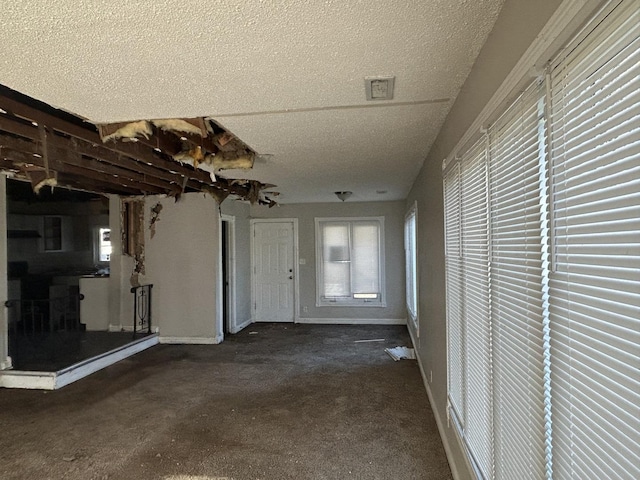 interior space with a textured ceiling and dark colored carpet