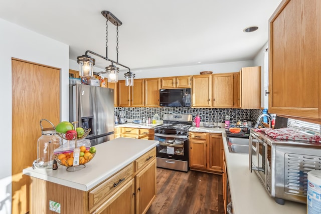 kitchen with dark wood-type flooring, sink, hanging light fixtures, tasteful backsplash, and stainless steel appliances