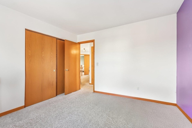 unfurnished bedroom featuring light colored carpet and a closet