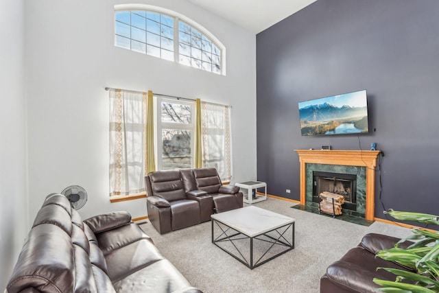 living room with carpet flooring, a high ceiling, and a premium fireplace