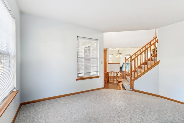 carpeted empty room with a chandelier