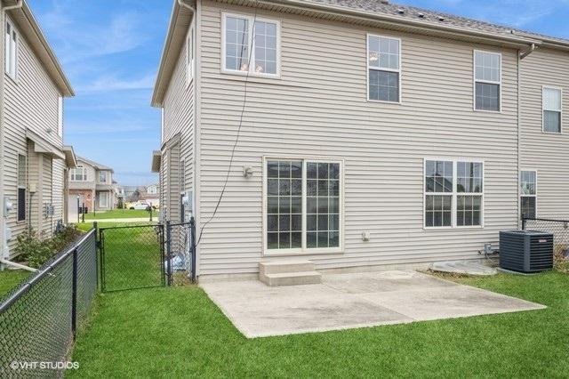 rear view of house with a patio area, a yard, and central AC