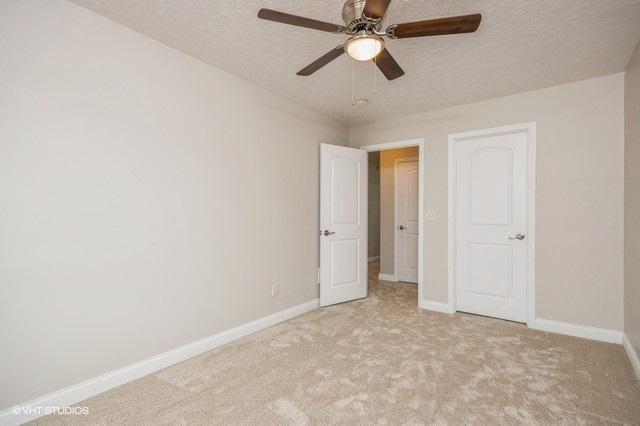 unfurnished bedroom featuring ceiling fan, a textured ceiling, and light carpet