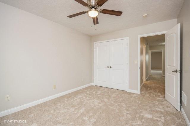 unfurnished bedroom with ceiling fan, a closet, light carpet, and a textured ceiling