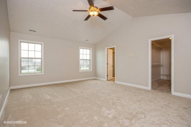 unfurnished bedroom with ceiling fan, a closet, a spacious closet, and multiple windows