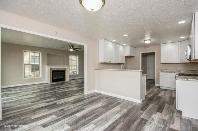 kitchen with a textured ceiling, white cabinetry, ceiling fan, and dark wood-type flooring