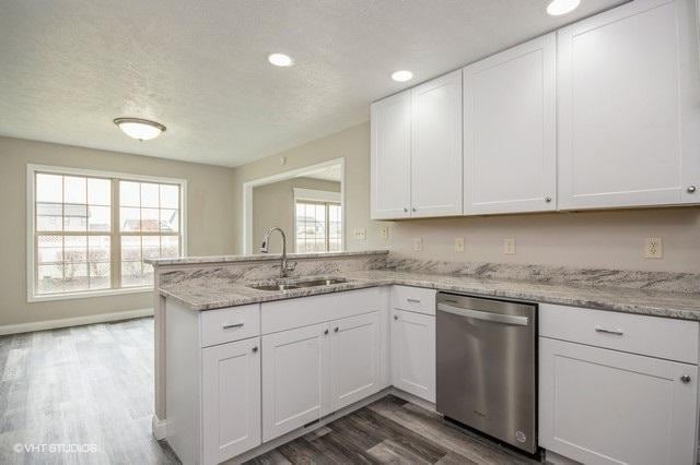 kitchen featuring white cabinets, stainless steel dishwasher, and a wealth of natural light