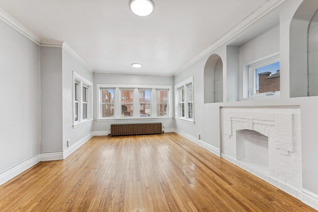 unfurnished living room featuring light wood-type flooring, crown molding, radiator, and a healthy amount of sunlight