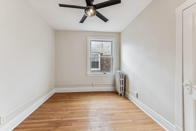 spare room with ceiling fan, radiator heating unit, and light hardwood / wood-style flooring