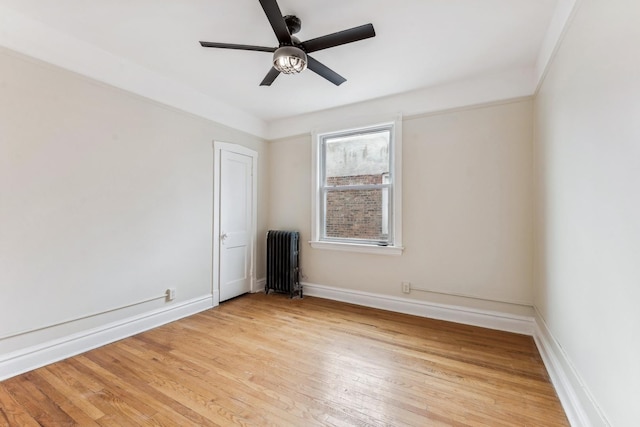 unfurnished room with ceiling fan, radiator, and light hardwood / wood-style flooring