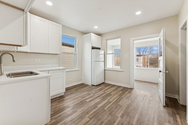 kitchen with white cabinetry, light hardwood / wood-style flooring, sink, and white refrigerator