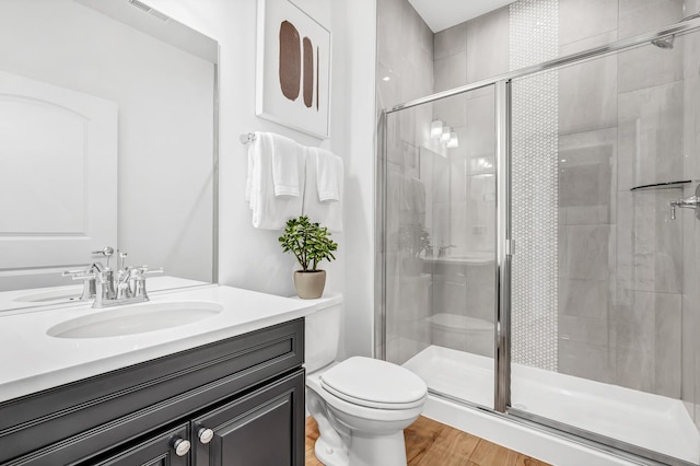 bathroom featuring hardwood / wood-style floors, toilet, an enclosed shower, and vanity