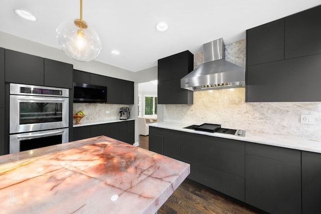 kitchen featuring wall chimney exhaust hood, tasteful backsplash, dark hardwood / wood-style flooring, decorative light fixtures, and appliances with stainless steel finishes