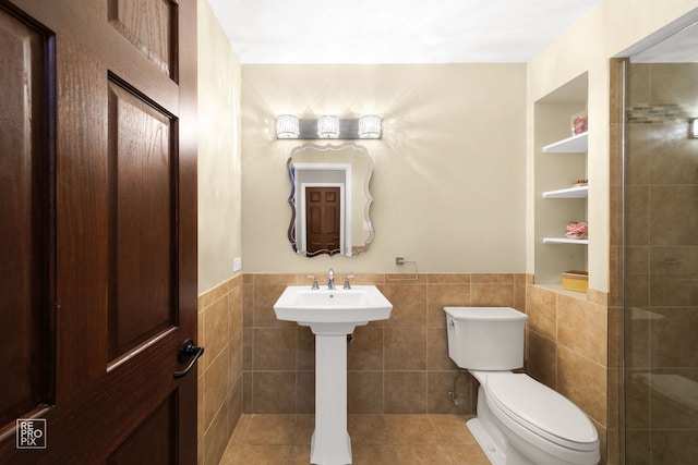 bathroom with tile patterned floors, toilet, and tile walls