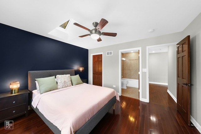 bedroom with a skylight, dark hardwood / wood-style flooring, ensuite bathroom, and ceiling fan