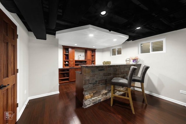 bar featuring dark stone countertops and dark hardwood / wood-style flooring