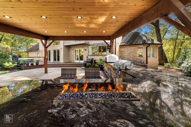 view of patio with grilling area, an outdoor fire pit, and a wooden deck