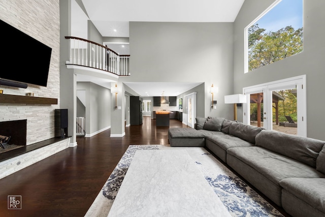 living room featuring a fireplace, french doors, a towering ceiling, and dark hardwood / wood-style floors