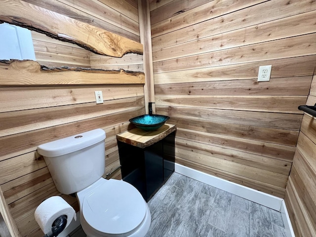 bathroom with hardwood / wood-style floors, toilet, and wooden walls