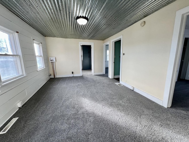 empty room featuring carpet flooring and wooden walls