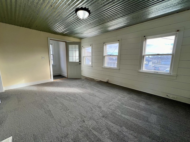 carpeted spare room with wood walls