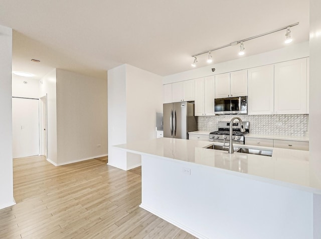 kitchen featuring white cabinetry, stainless steel appliances, kitchen peninsula, light hardwood / wood-style floors, and decorative backsplash