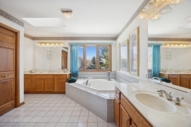 bathroom with tile patterned floors, crown molding, a skylight, vanity, and tiled tub