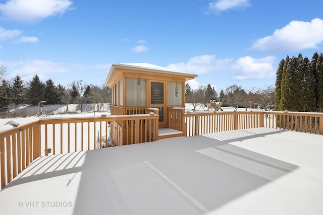 snow covered deck featuring a sunroom